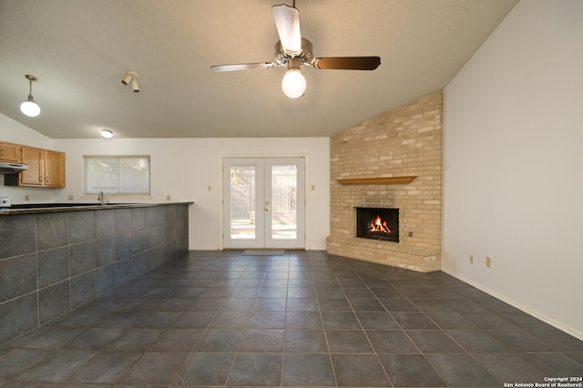 unfurnished living room with ceiling fan, french doors, dark tile patterned flooring, and lofted ceiling