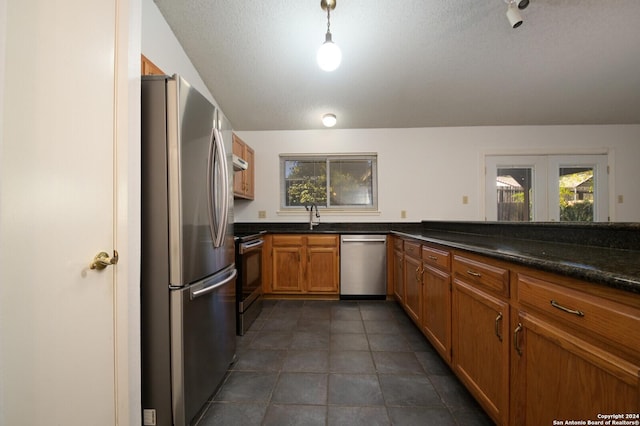 kitchen featuring decorative light fixtures, a wealth of natural light, sink, and appliances with stainless steel finishes