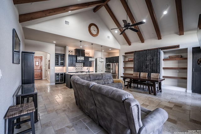 living room featuring ceiling fan, beam ceiling, sink, and high vaulted ceiling