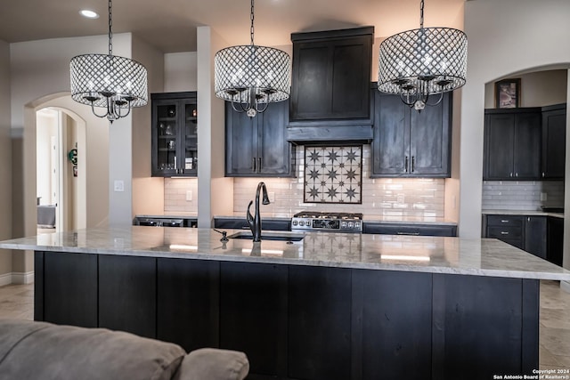 kitchen featuring pendant lighting, light stone counters, sink, and stainless steel range oven