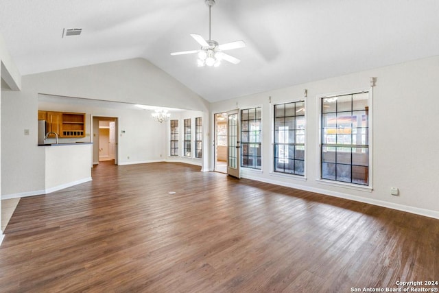 unfurnished living room featuring plenty of natural light, dark hardwood / wood-style flooring, lofted ceiling, and ceiling fan with notable chandelier