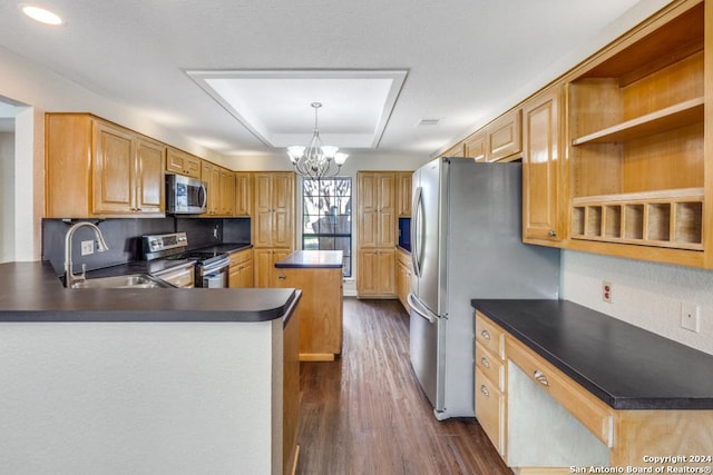 kitchen with dark wood-type flooring, sink, appliances with stainless steel finishes, kitchen peninsula, and a chandelier