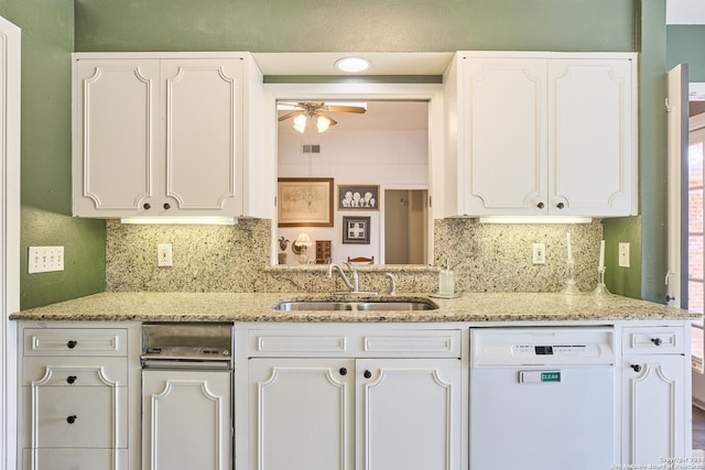 kitchen with ceiling fan, sink, light stone counters, white dishwasher, and white cabinets