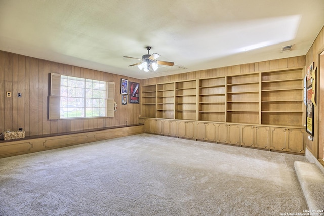 unfurnished room featuring wood walls, ceiling fan, and light carpet