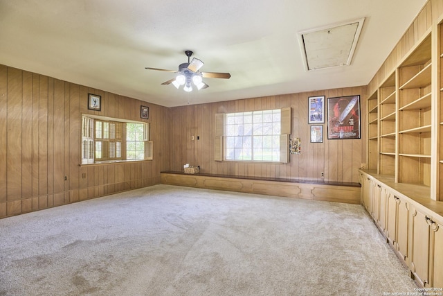 empty room featuring ceiling fan, light carpet, and wooden walls