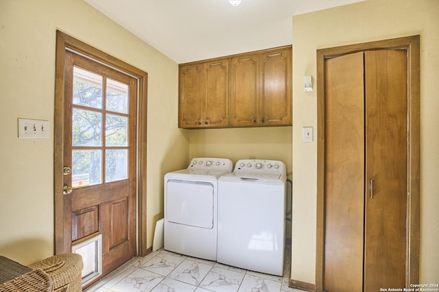 clothes washing area with washer and clothes dryer and cabinets