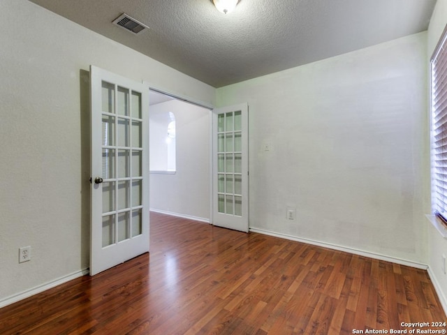 empty room featuring dark hardwood / wood-style floors, a healthy amount of sunlight, and french doors