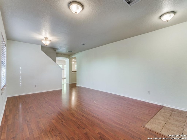 unfurnished room with dark hardwood / wood-style flooring and a textured ceiling