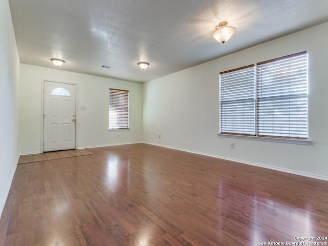 foyer entrance with a textured ceiling and dark hardwood / wood-style floors