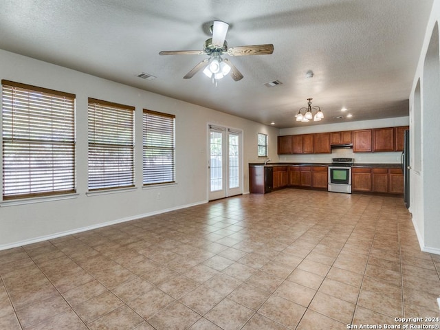 kitchen featuring light tile patterned floors, ceiling fan with notable chandelier, stainless steel stove, and a textured ceiling