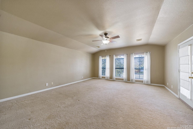 carpeted spare room featuring a textured ceiling, ceiling fan, and vaulted ceiling