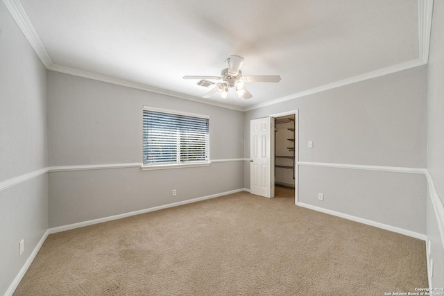 unfurnished bedroom featuring ceiling fan, a spacious closet, light carpet, a closet, and ornamental molding