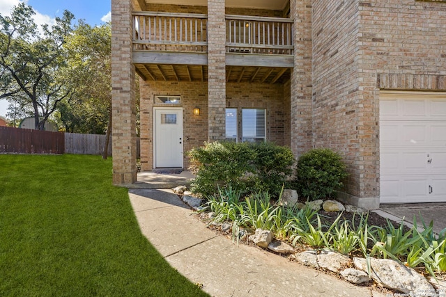 property entrance with a balcony, a garage, and a lawn