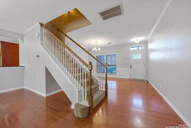 foyer entrance featuring wood-type flooring, an inviting chandelier, and ornamental molding