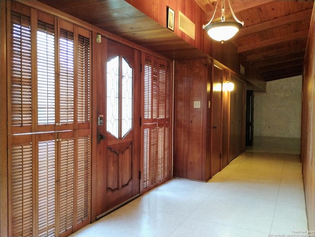 entrance foyer featuring beamed ceiling, wooden walls, and wood ceiling