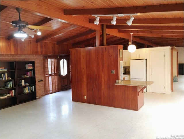 kitchen with kitchen peninsula, beam ceiling, wooden ceiling, white fridge, and wood walls