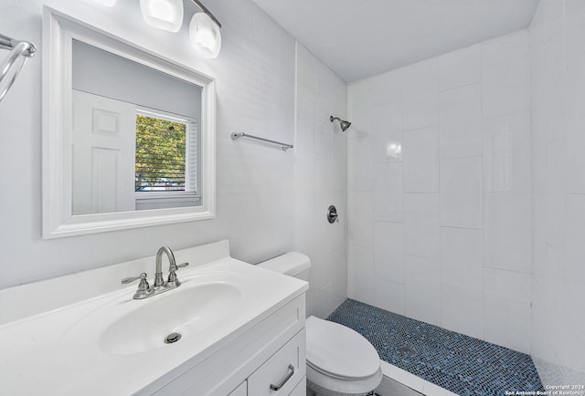 bathroom featuring vanity, toilet, and a tile shower