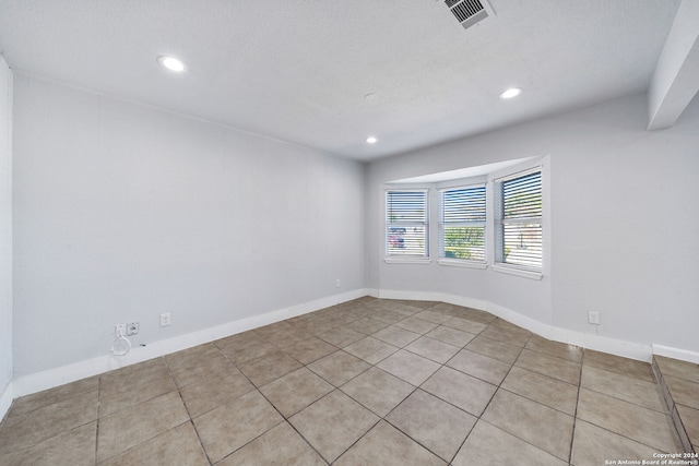 tiled empty room featuring a textured ceiling