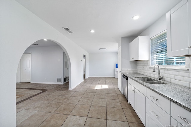 kitchen featuring dishwasher, backsplash, sink, light tile patterned flooring, and white cabinetry