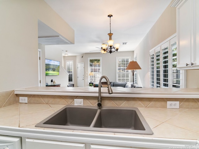 kitchen with white cabinets, pendant lighting, sink, and an inviting chandelier