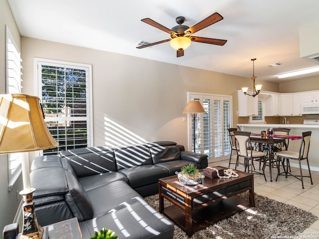 living room featuring light tile patterned floors and ceiling fan with notable chandelier