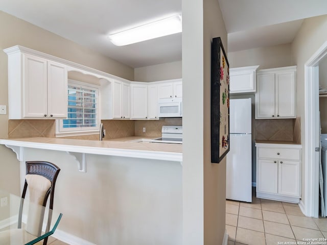 kitchen featuring kitchen peninsula, white appliances, white cabinetry, and a breakfast bar area