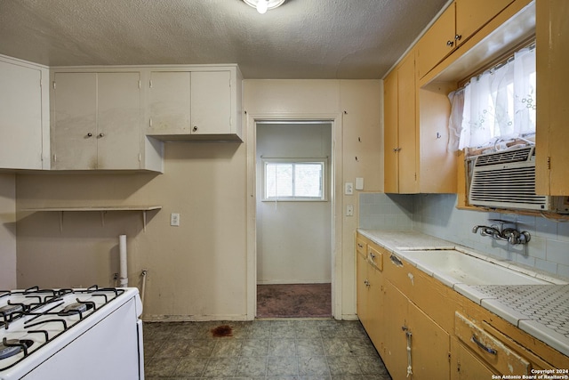 kitchen with backsplash, a textured ceiling, cooling unit, sink, and white range with gas stovetop