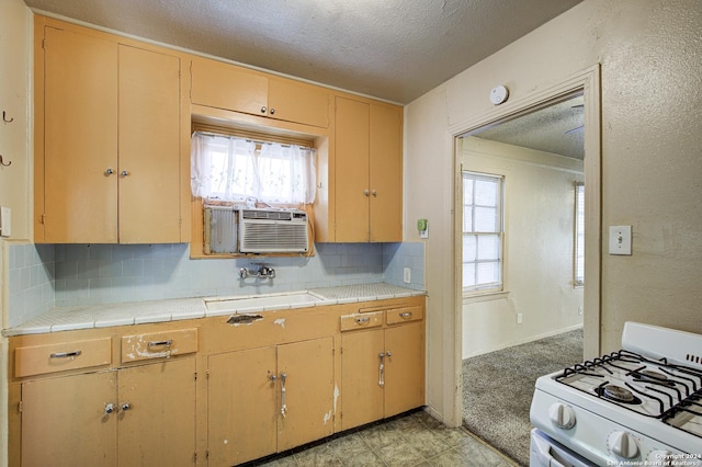 kitchen with backsplash, a textured ceiling, sink, tile countertops, and white gas stove