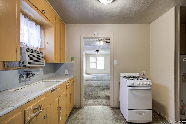 kitchen with a textured ceiling, white gas stove, decorative backsplash, and sink