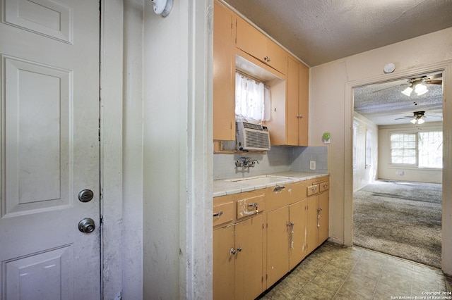 kitchen featuring tasteful backsplash, a textured ceiling, light colored carpet, cooling unit, and sink