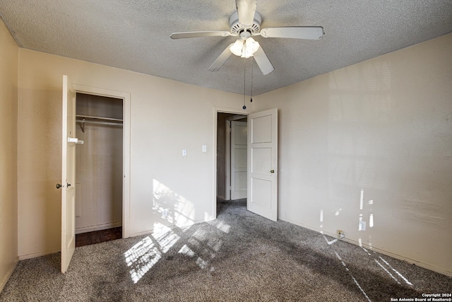 unfurnished bedroom featuring dark colored carpet, a textured ceiling, a closet, and ceiling fan