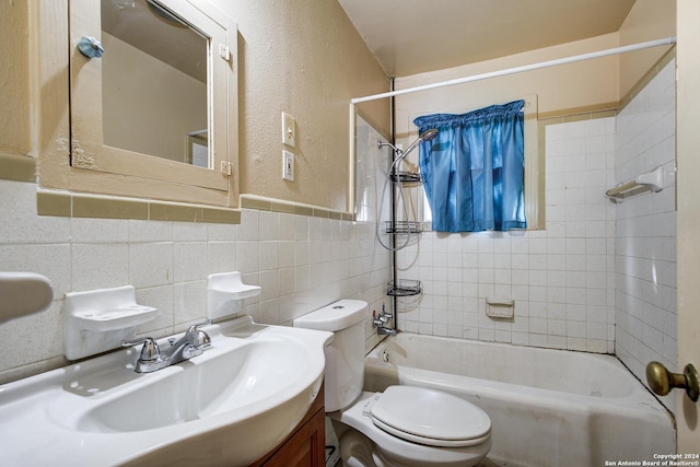 full bathroom with vanity, tiled shower / bath combo, tile walls, and toilet