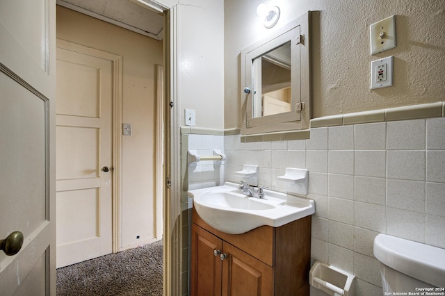 bathroom featuring vanity, tile walls, and toilet