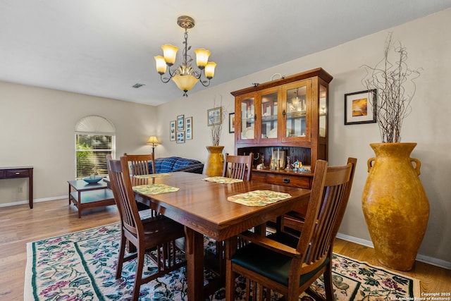 dining area with light wood-style floors, a notable chandelier, and baseboards