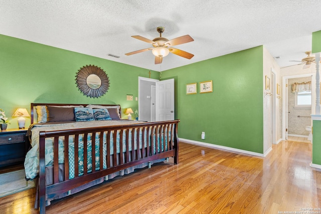 bedroom featuring visible vents, a ceiling fan, a textured ceiling, wood finished floors, and baseboards