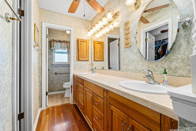 full bath featuring a sink, toilet, and wallpapered walls