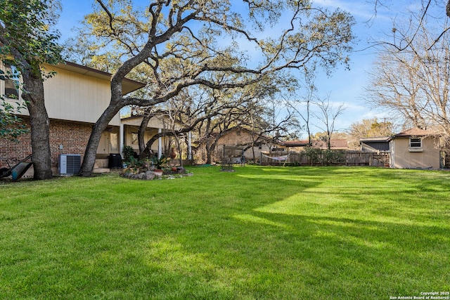 view of yard with central AC and fence