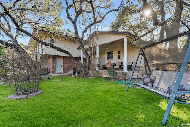 back of property featuring a ceiling fan, a trampoline, a yard, a patio area, and brick siding