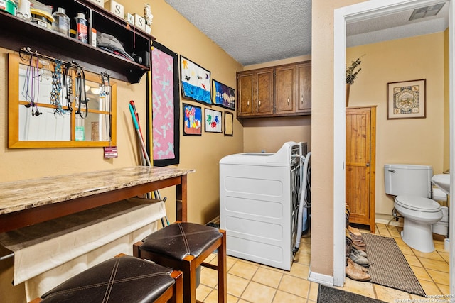 laundry room with light tile patterned floors, a textured ceiling, visible vents, and baseboards