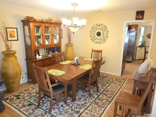 dining room featuring baseboards, visible vents, and a notable chandelier