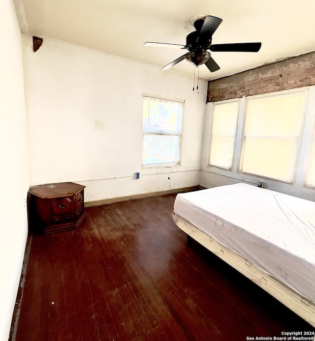 unfurnished bedroom with ceiling fan and dark wood-type flooring