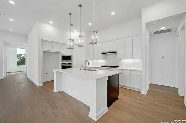 kitchen featuring white cabinets, stainless steel appliances, an island with sink, and light hardwood / wood-style flooring