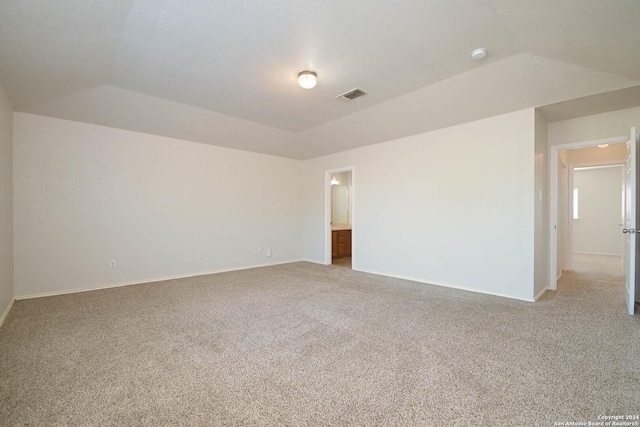 carpeted empty room with vaulted ceiling