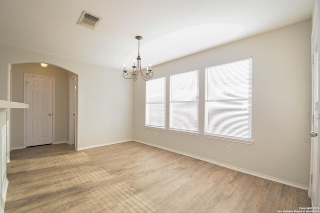 empty room featuring light hardwood / wood-style flooring and a notable chandelier