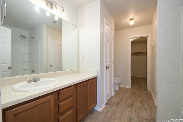 bathroom featuring walk in shower, vanity, wood-type flooring, and toilet