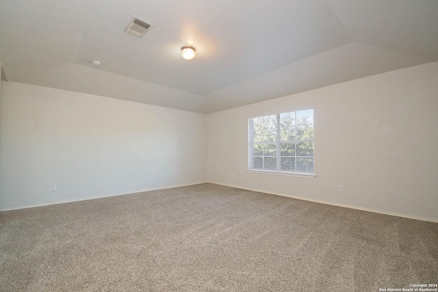 carpeted spare room featuring lofted ceiling