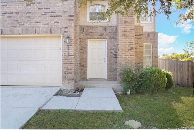 property entrance with a lawn and a garage