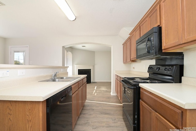 kitchen featuring black appliances, light wood-type flooring, and sink