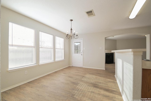 unfurnished dining area with wood-type flooring and a notable chandelier