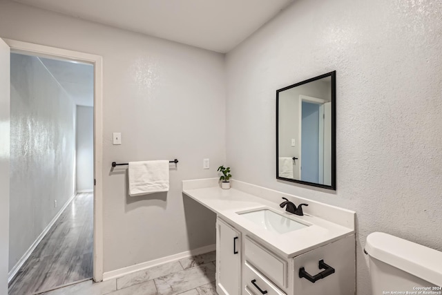 bathroom featuring wood-type flooring, vanity, and toilet